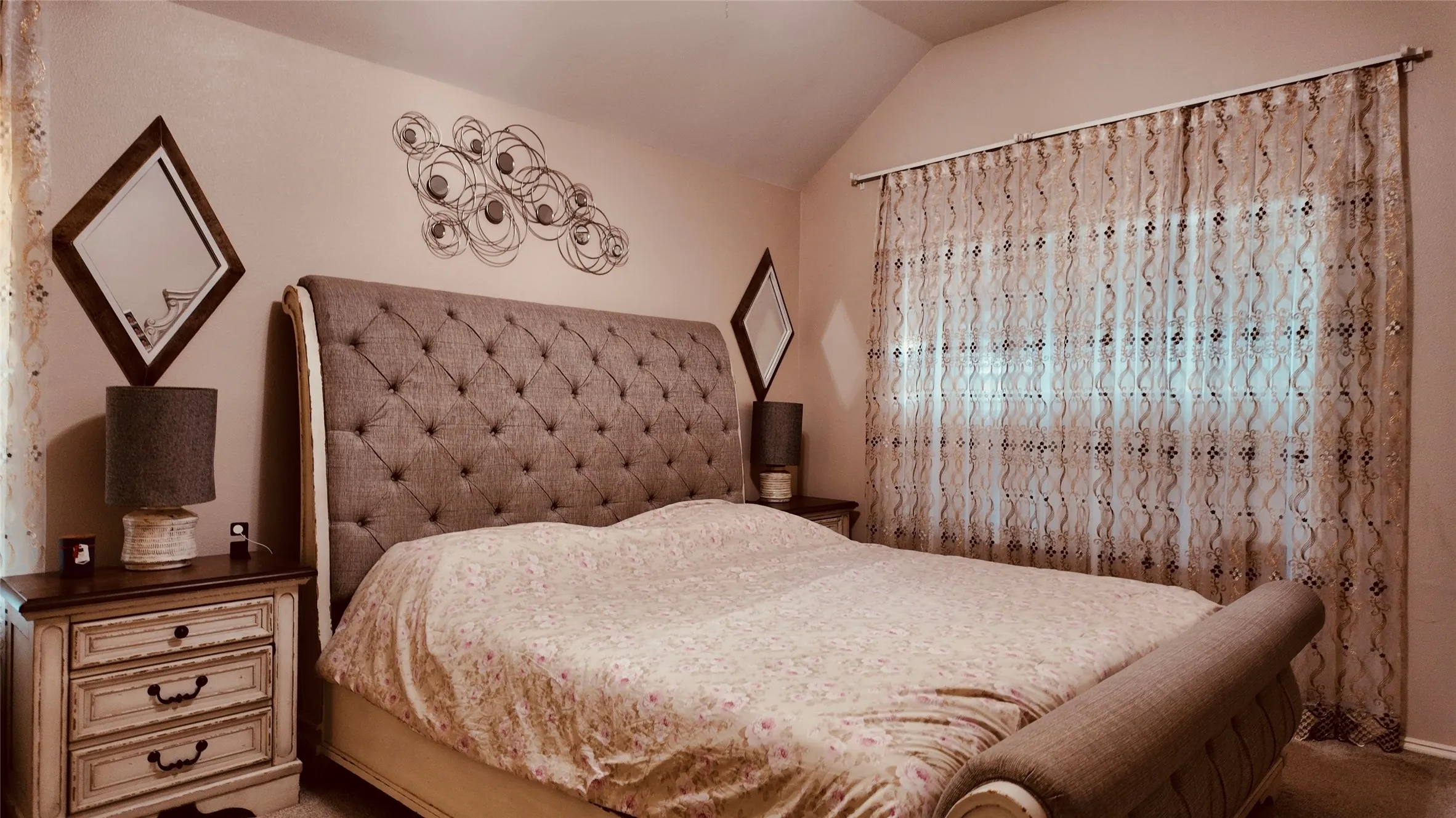 Vaulted ceiling with an expansive window featuring sheer patterned drapes
