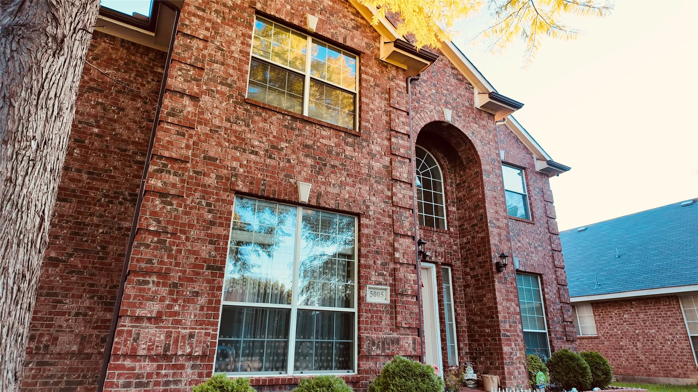 Brick exterior facade featuring an arched entry and multiple window styles