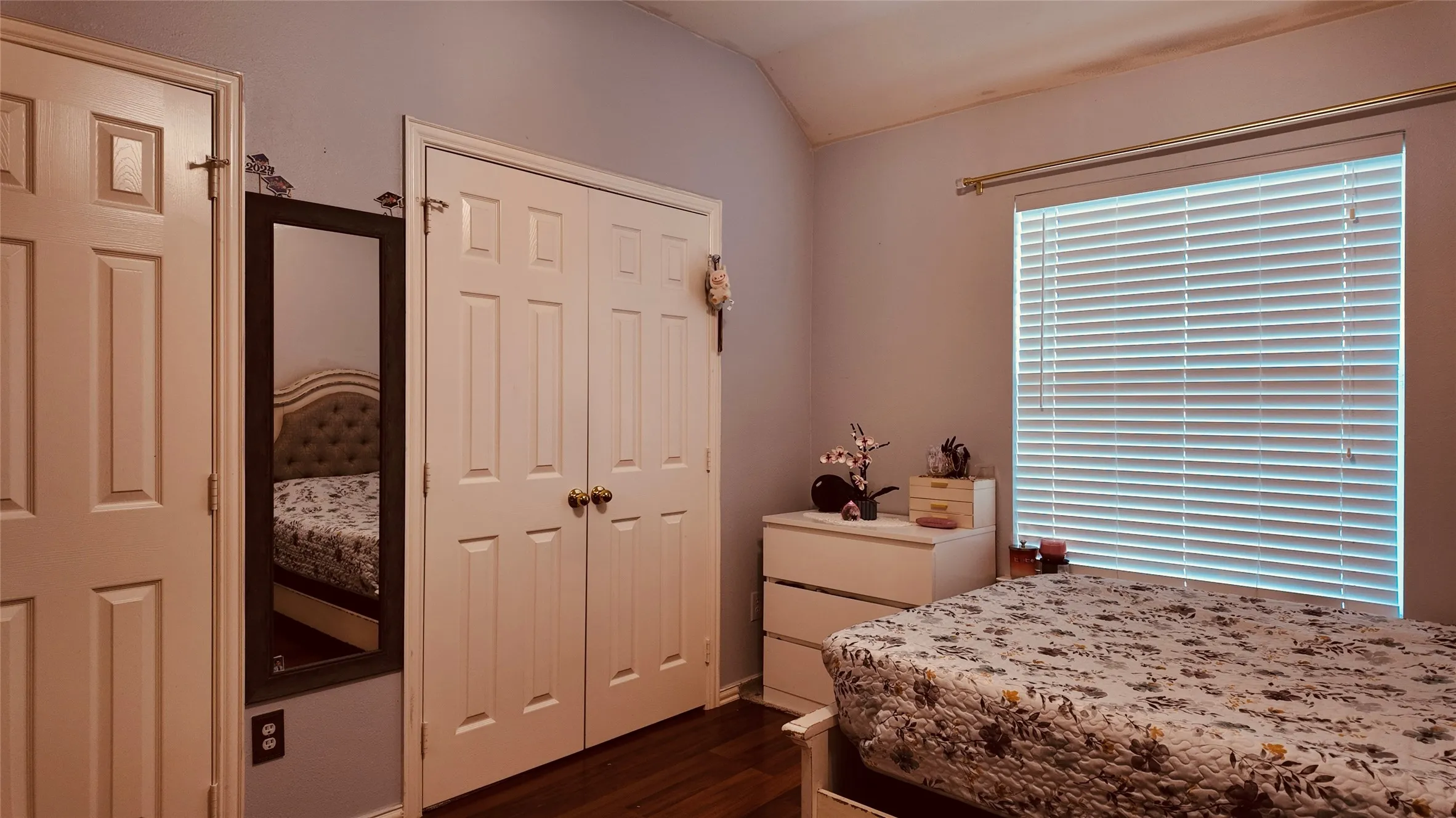 Wood-finish flooring, paneled interior doors, and a window with horizontal blinds