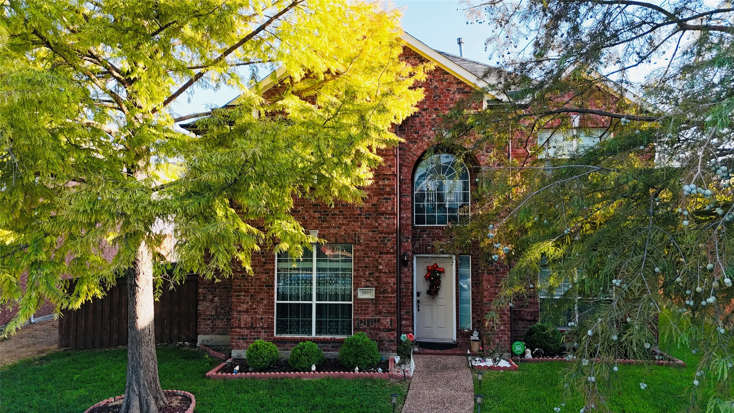 Two-story brick exterior with an arched window, a white entry door, a stone pathway, and a manicured front lawn