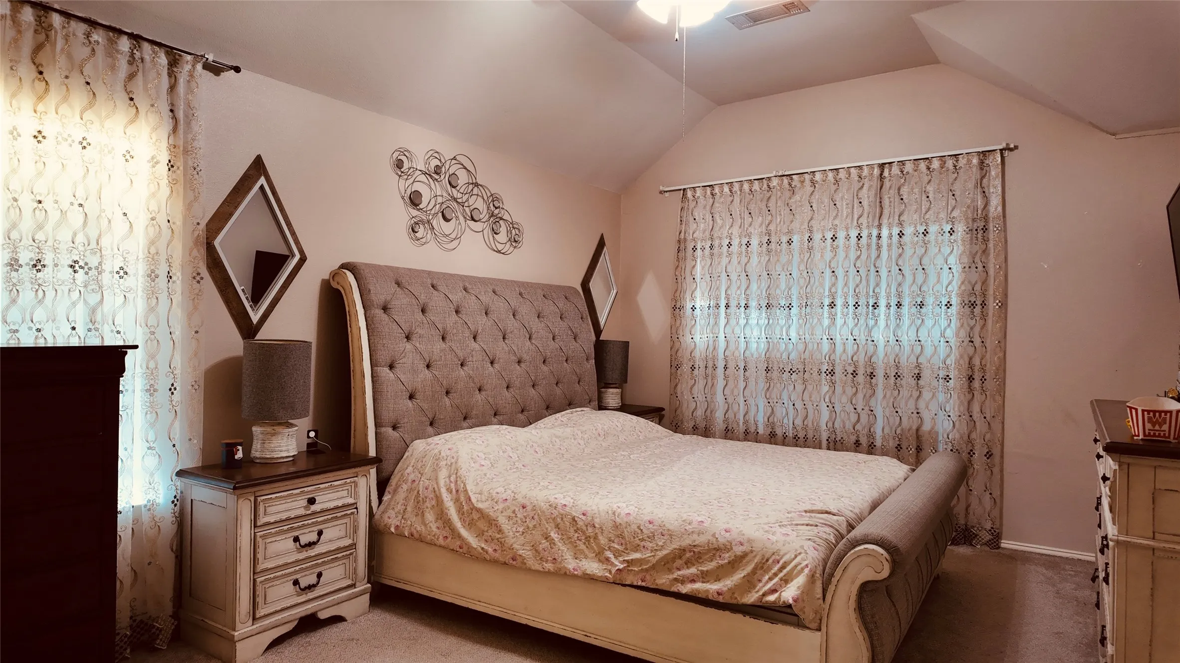 Vaulted ceiling with ceiling fan, wall-to-wall carpeting, and sheer window treatments