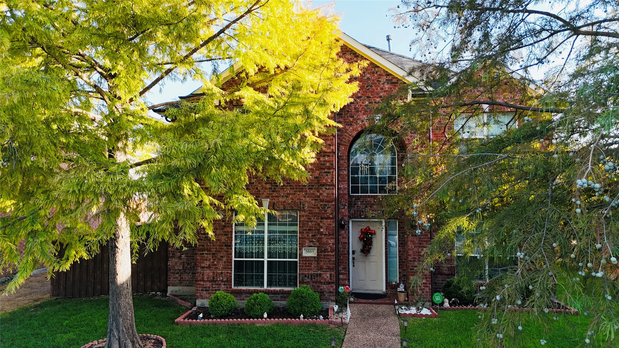 Brick exterior with an arched window, white front door, and manicured landscaping