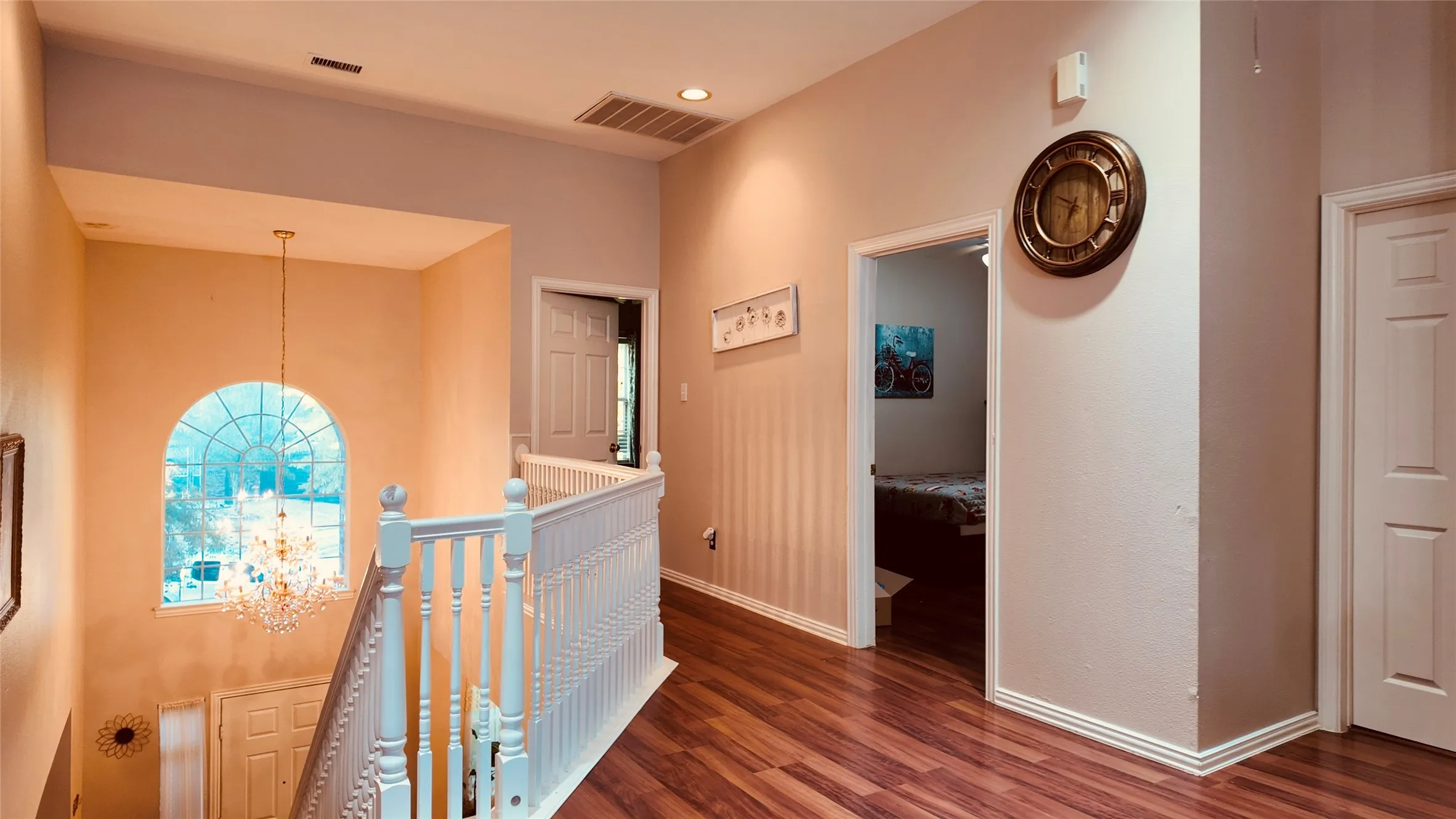Two-story foyer with an arched window, crystal chandelier, and wood-finish flooring