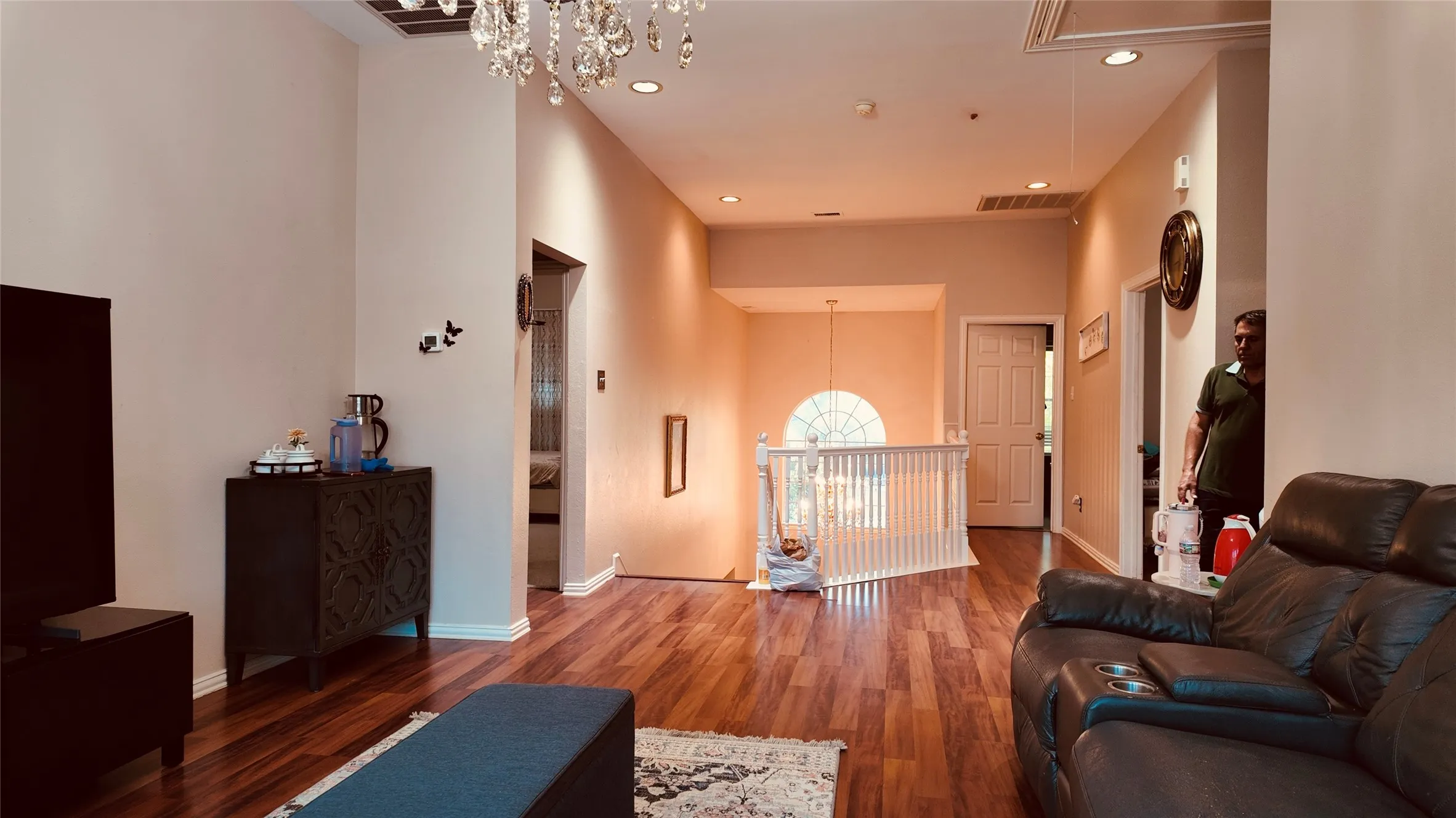Wood-finish flooring throughout, with a decorative chandelier and recessed lighting