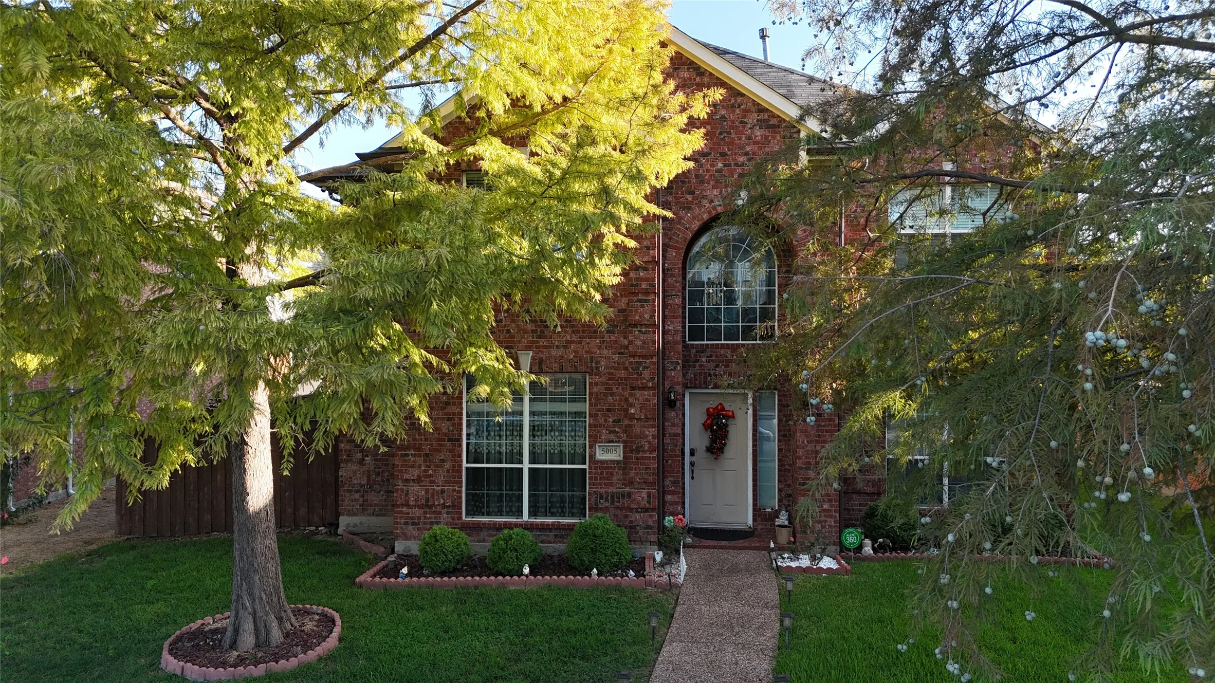 Brick exterior with an arched window, white front door, and a concrete pathway