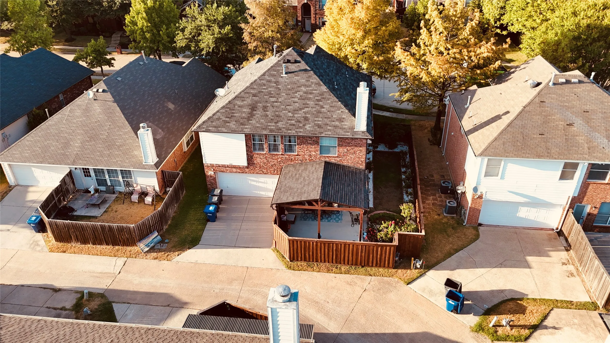 Brick exterior home with an attached garage, a covered patio, and a fenced backyard