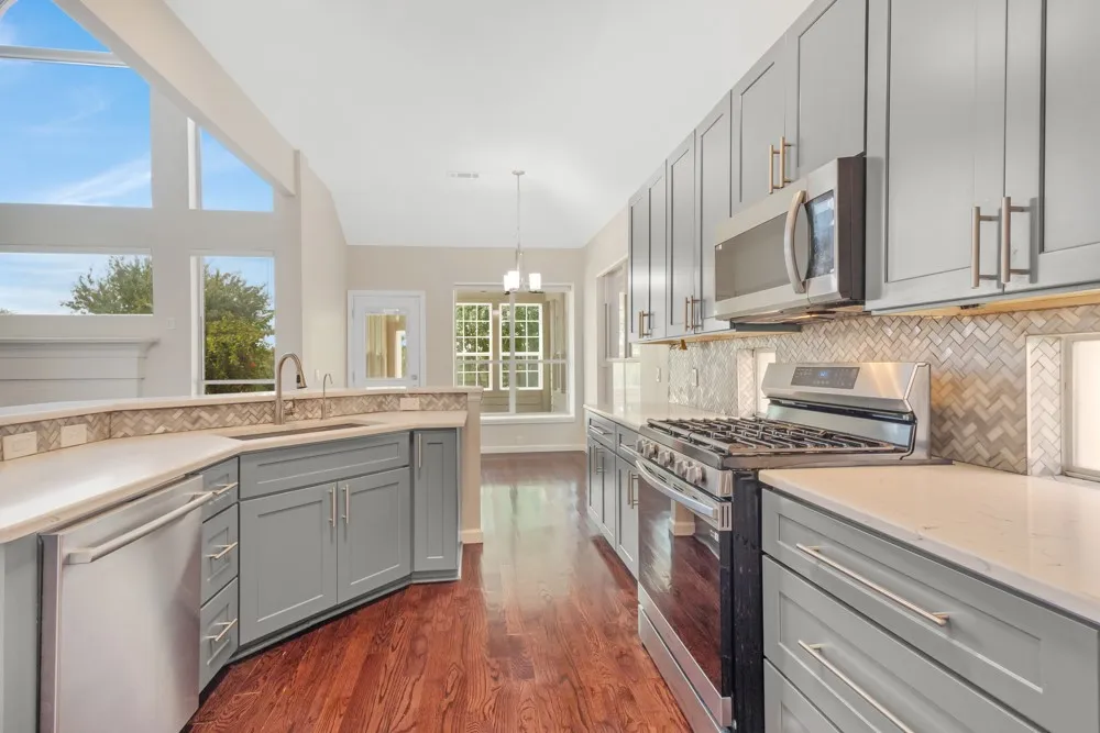 Chef's kitchen featuring stainless steel gas range, dual refrigerator drawers, soft-close cabinetry with brushed nickel hardware, and quartz countertops