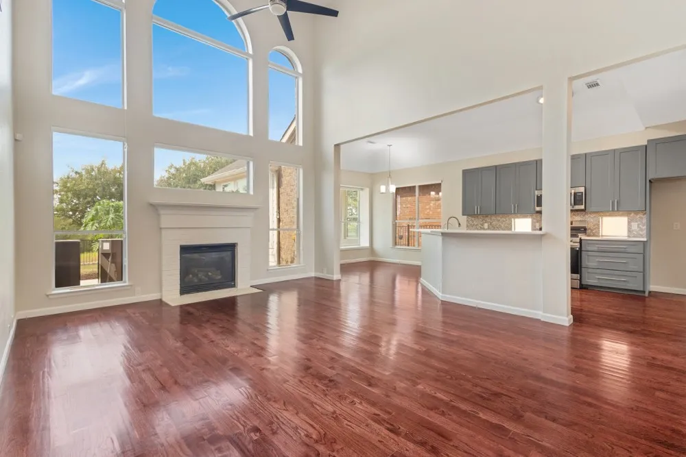 Two-story living area with arched windows, a fireplace, and wood-finish flooring