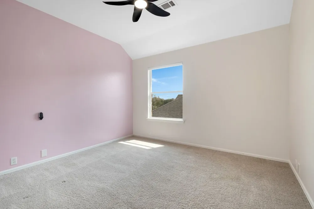 Vaulted ceiling with a ceiling fan, carpet flooring, and a single window