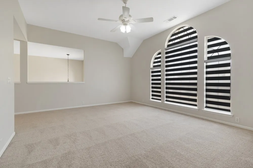 Spacious room featuring vaulted ceilings, recessed wall opening, and carpet flooring
