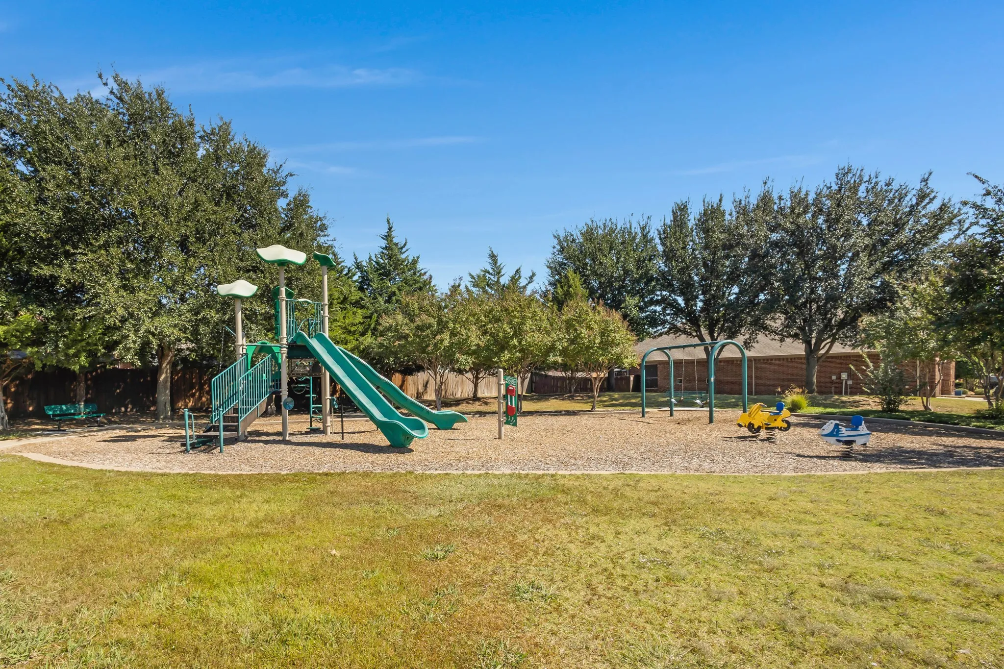 Expansive outdoor play area featuring a multi-level playset with slides, swings, and spring riders