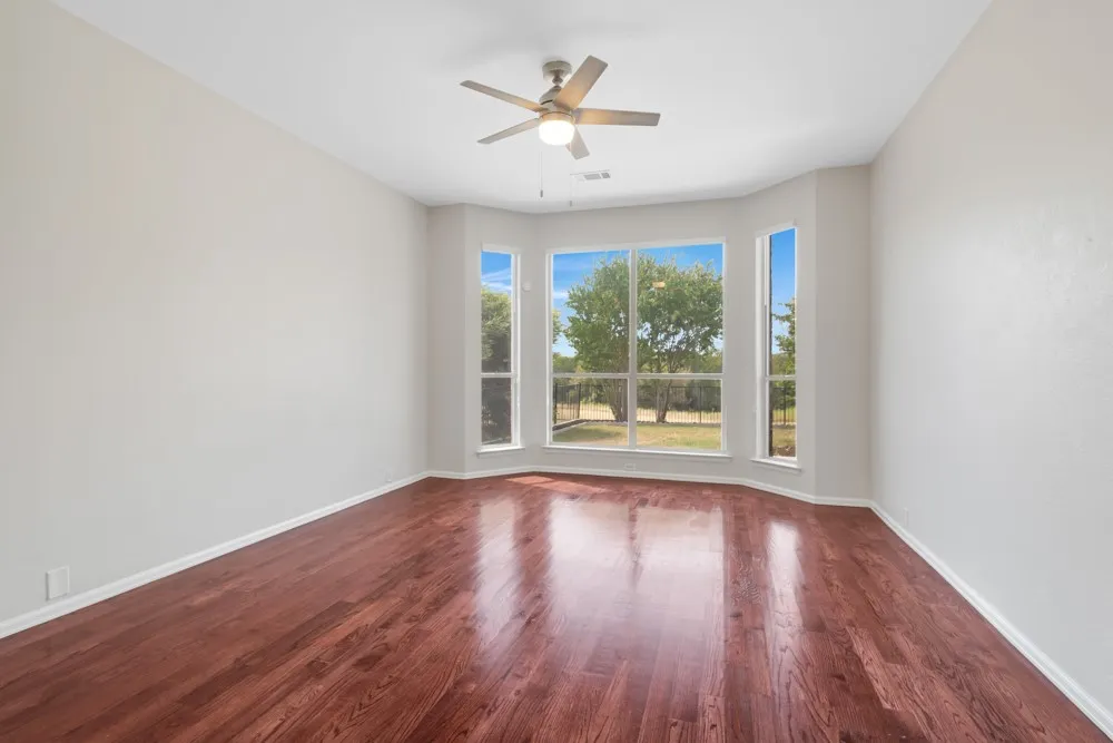 Wood-finish flooring, bay window, ceiling fan, and painted walls