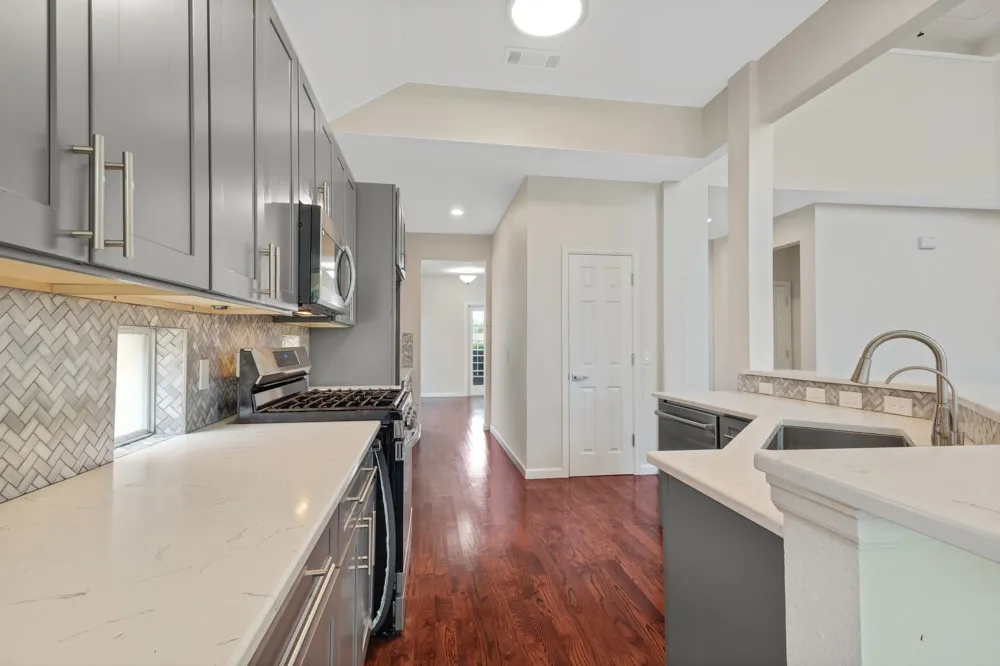 Kitchen featuring gray cabinetry, white countertops, a herringbone tile backsplash, and stainless steel appliances