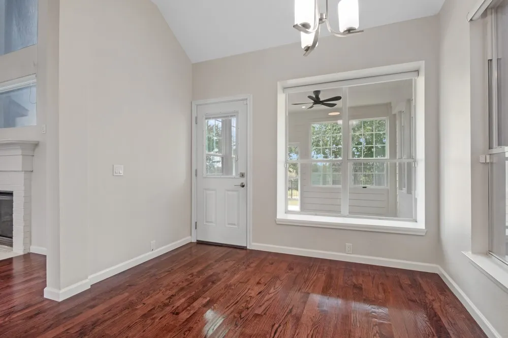 Wood-finish flooring, white trim, a white paneled door with an upper glass pane, and a large window with white framing