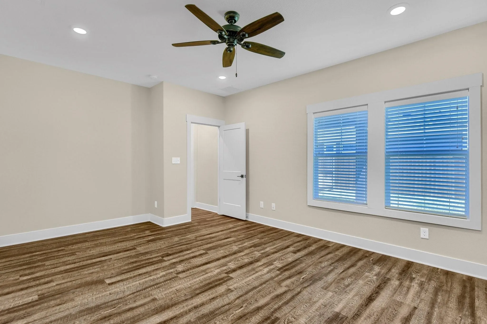 Wood-finish flooring, two windows with blinds, recessed lighting, and a ceiling fan
