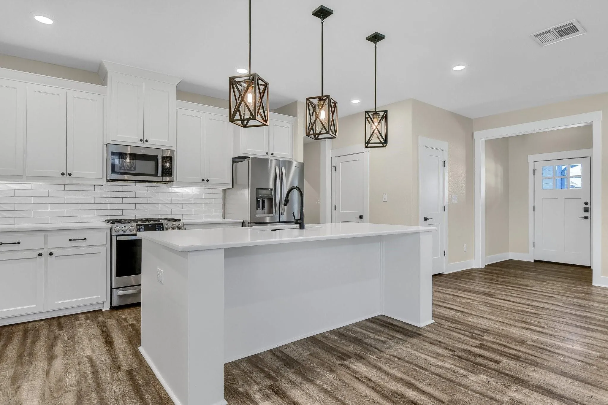 Well-appointed kitchen featuring a center island, stainless steel appliances, white cabinetry, and subway tile backsplash