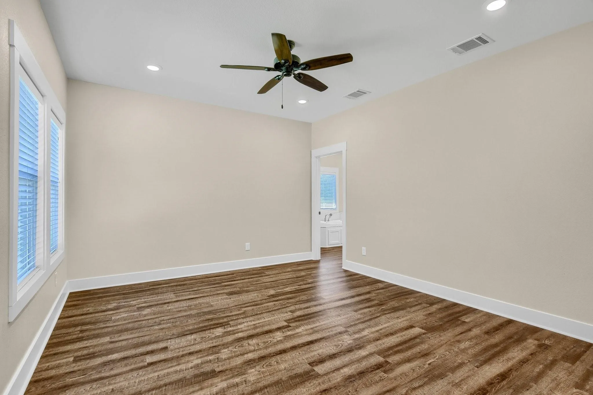 Spacious room featuring wood-finish flooring, recessed lighting, and a ceiling fan
