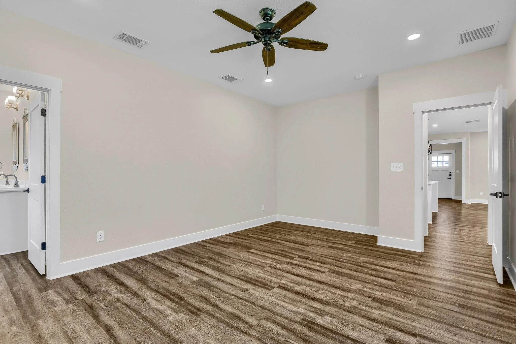 Wood-finish flooring, ceiling fan, recessed lighting, and white trim throughout