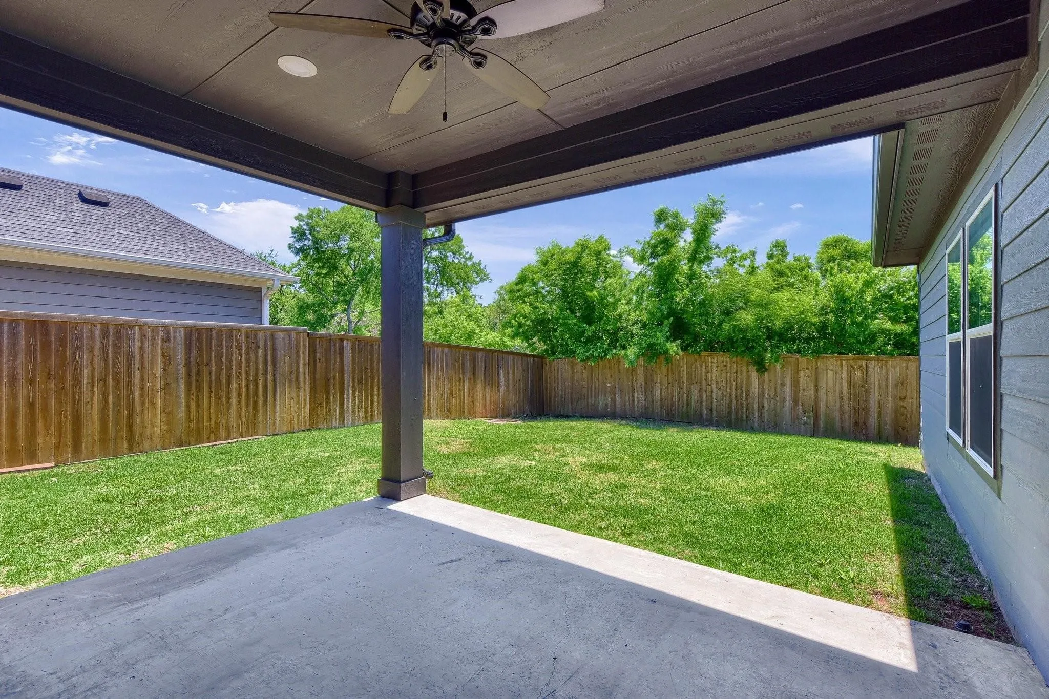 Covered concrete patio with a ceiling fan, recessed lighting, and a wood privacy fence