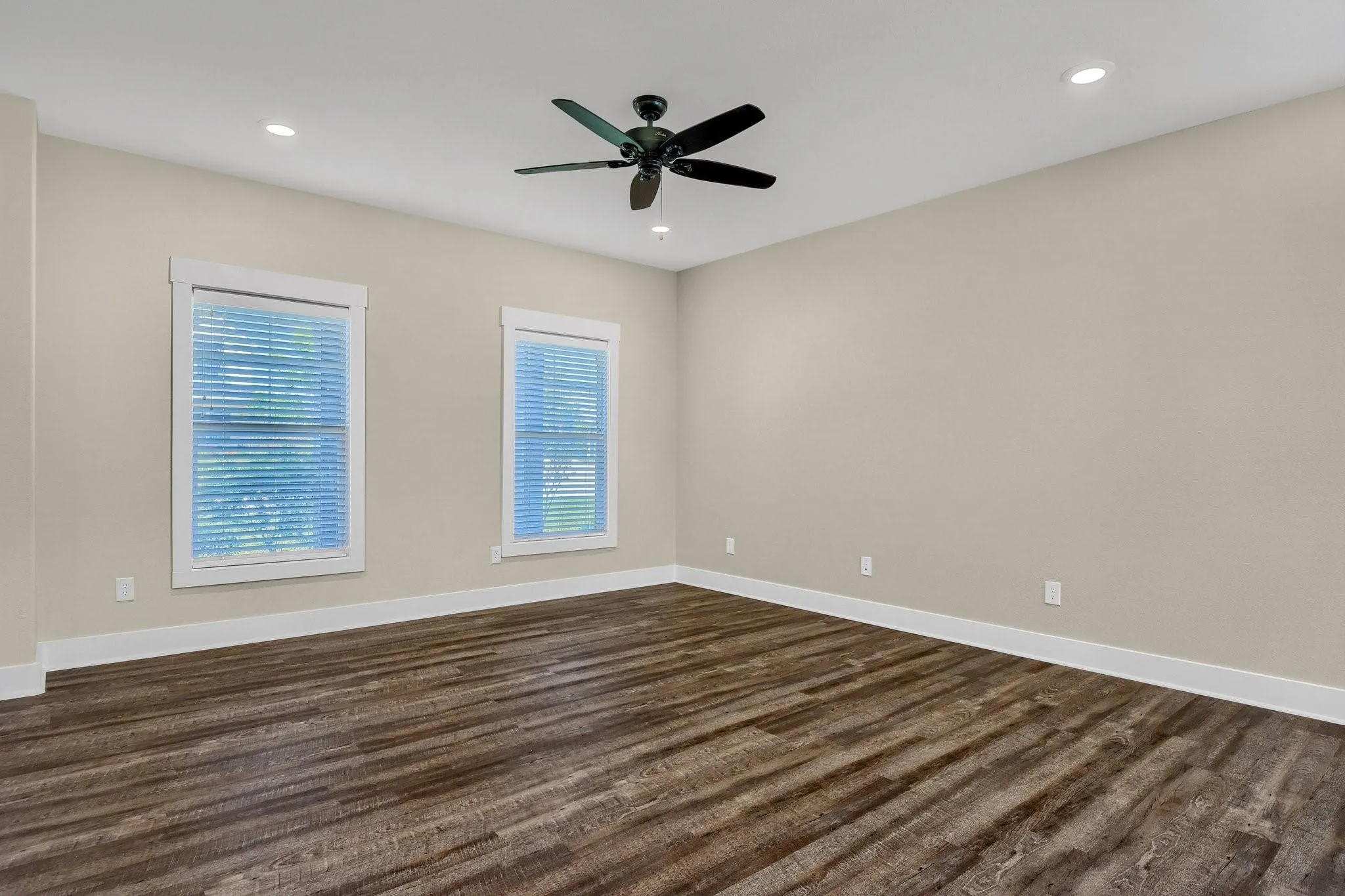 Recessed lighting, wood-finish flooring, two windows with blinds, a ceiling fan, and light neutral wall tones