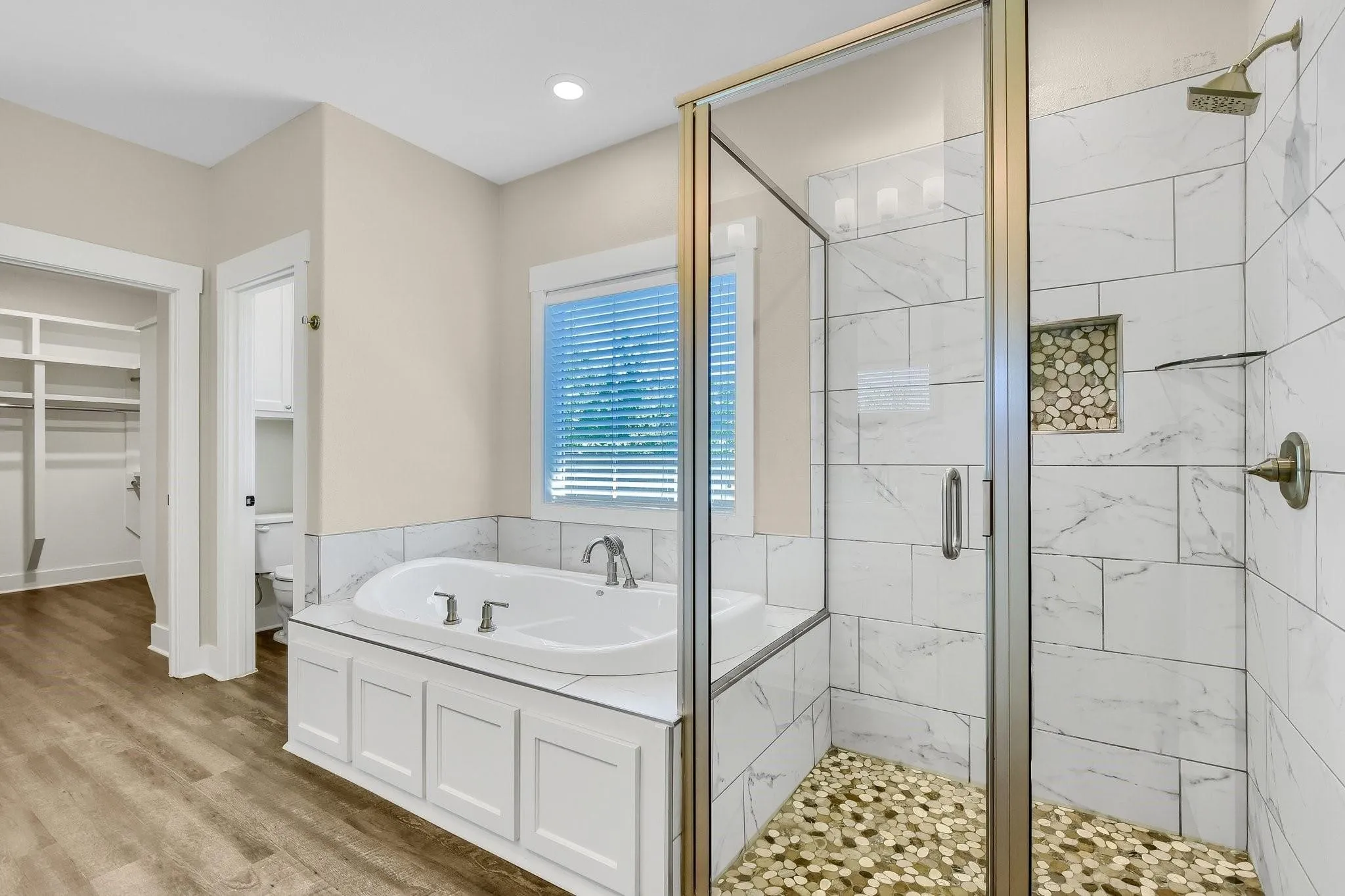 Walk-in shower with glass enclosure, pebble floor, and tiled walls