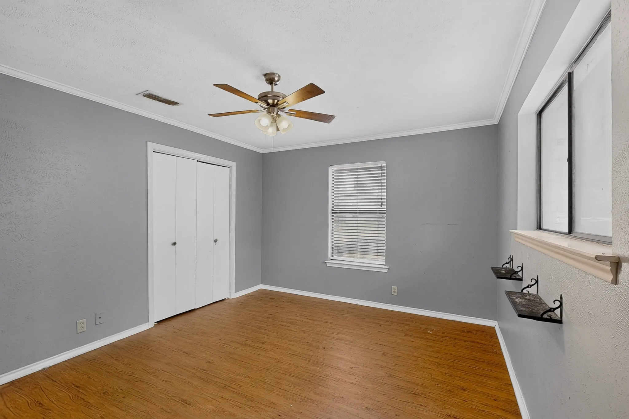 Wood-finish flooring, ceiling fan with integrated lighting, window with blinds, and bi-fold closet doors