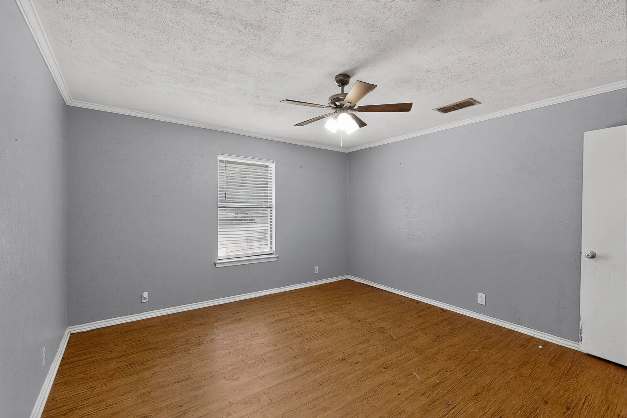 Wood-finish flooring, ceiling fan with integrated lighting, window with blinds, and painted walls