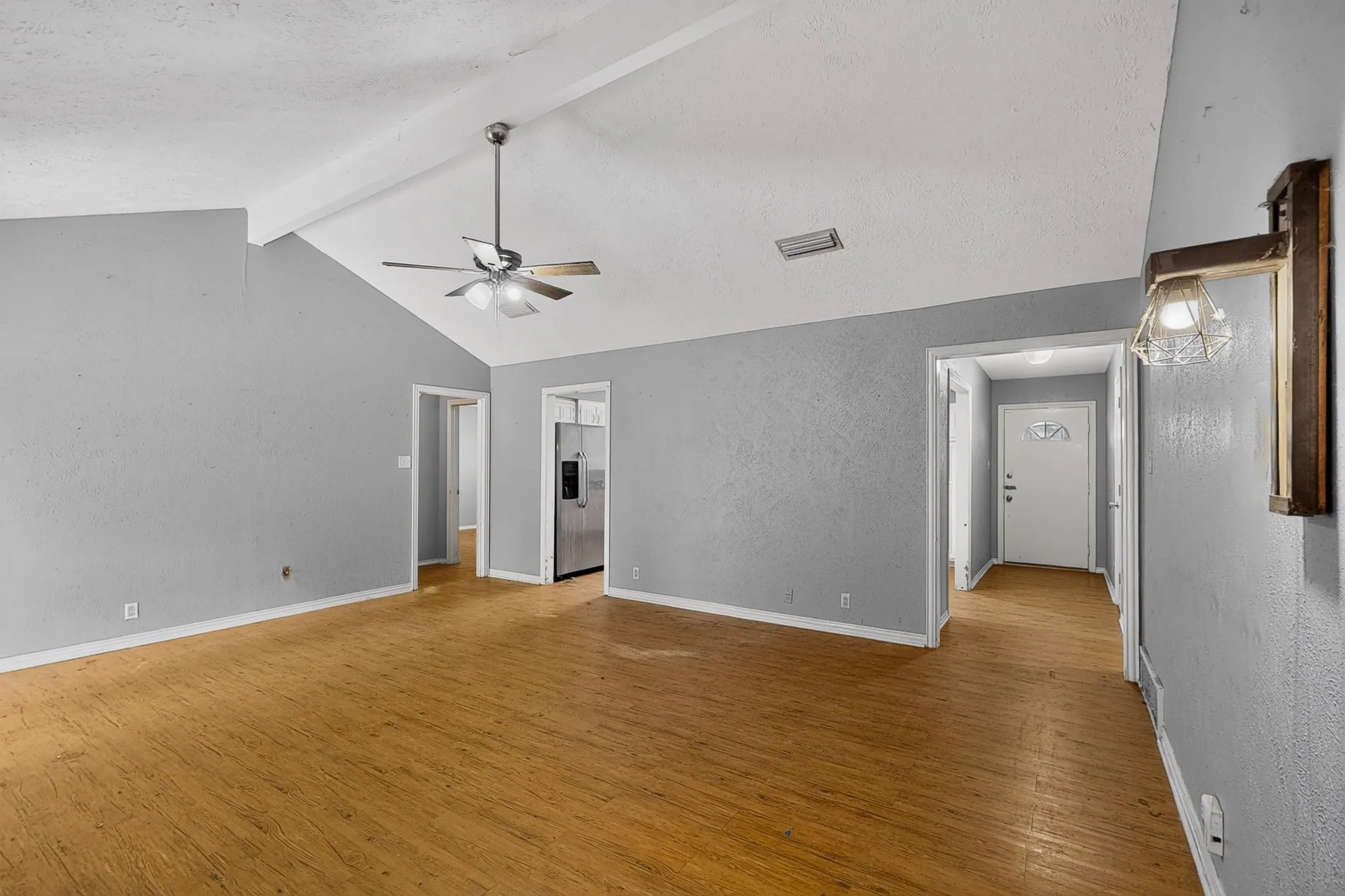 Vaulted ceiling with exposed beam, wood-finish flooring, ceiling fan with integrated lighting, wall-mounted sconce, and recessed lighting