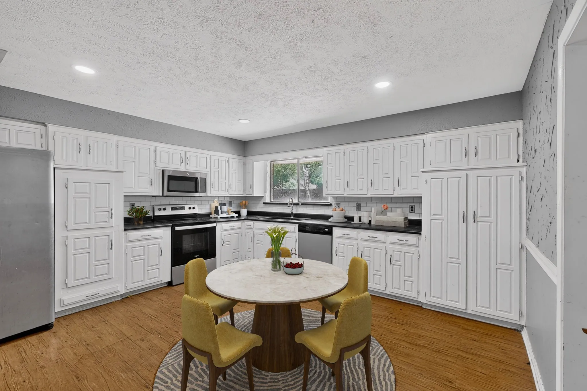 Kitchen featuring extensive white cabinetry, black countertops, stainless steel appliances, and wood-finish flooring