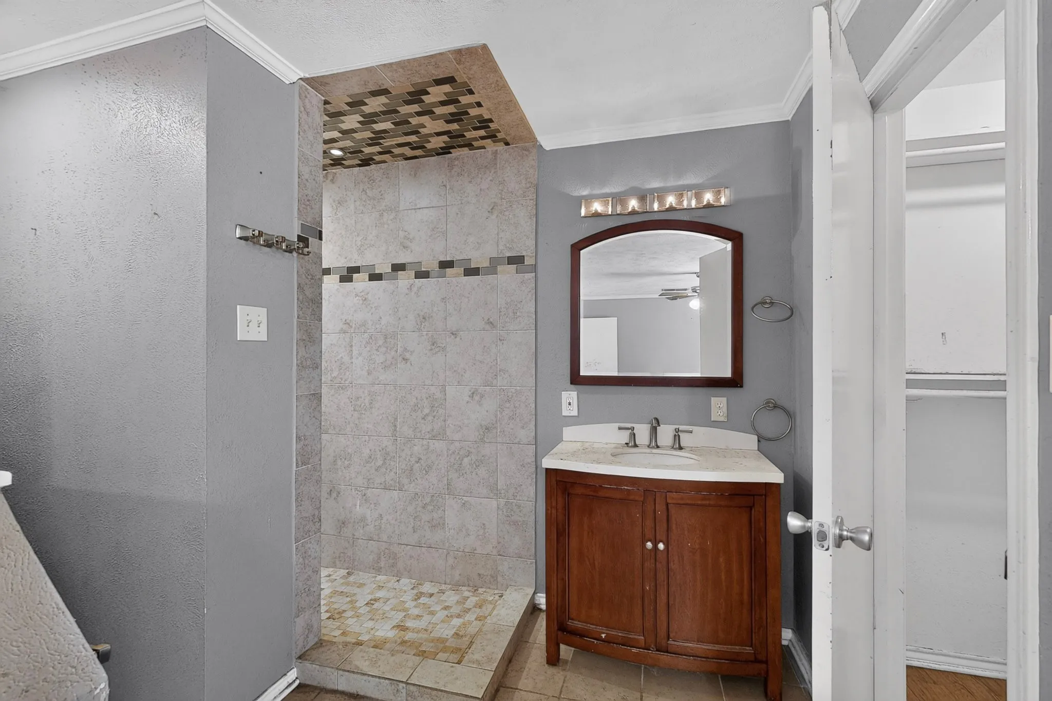 Tiled shower enclosure featuring a mosaic accent band and a patterned ceiling insert