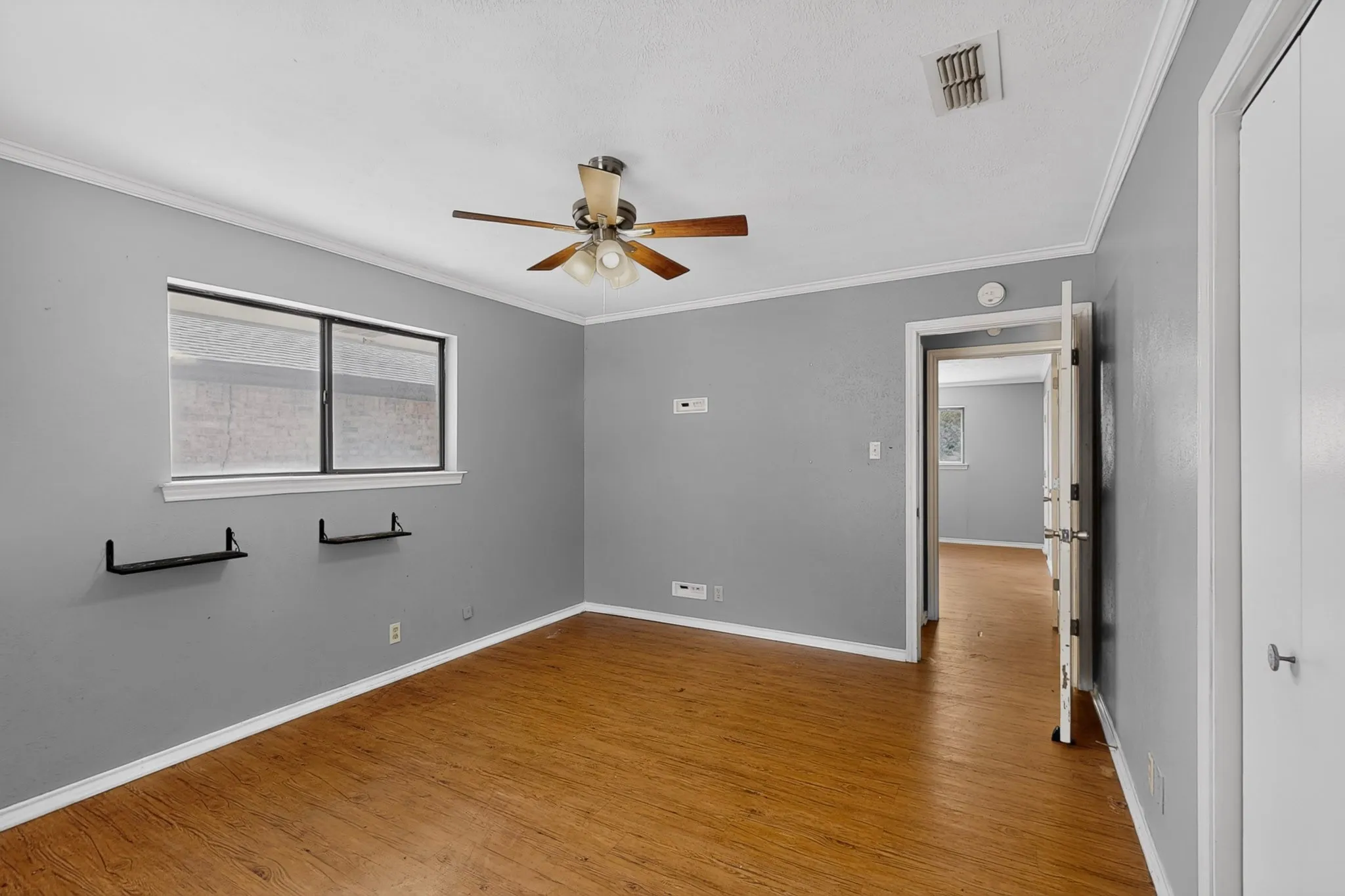 Wood-finish flooring, ceiling fan with integrated lighting, window with blinds, and white trim