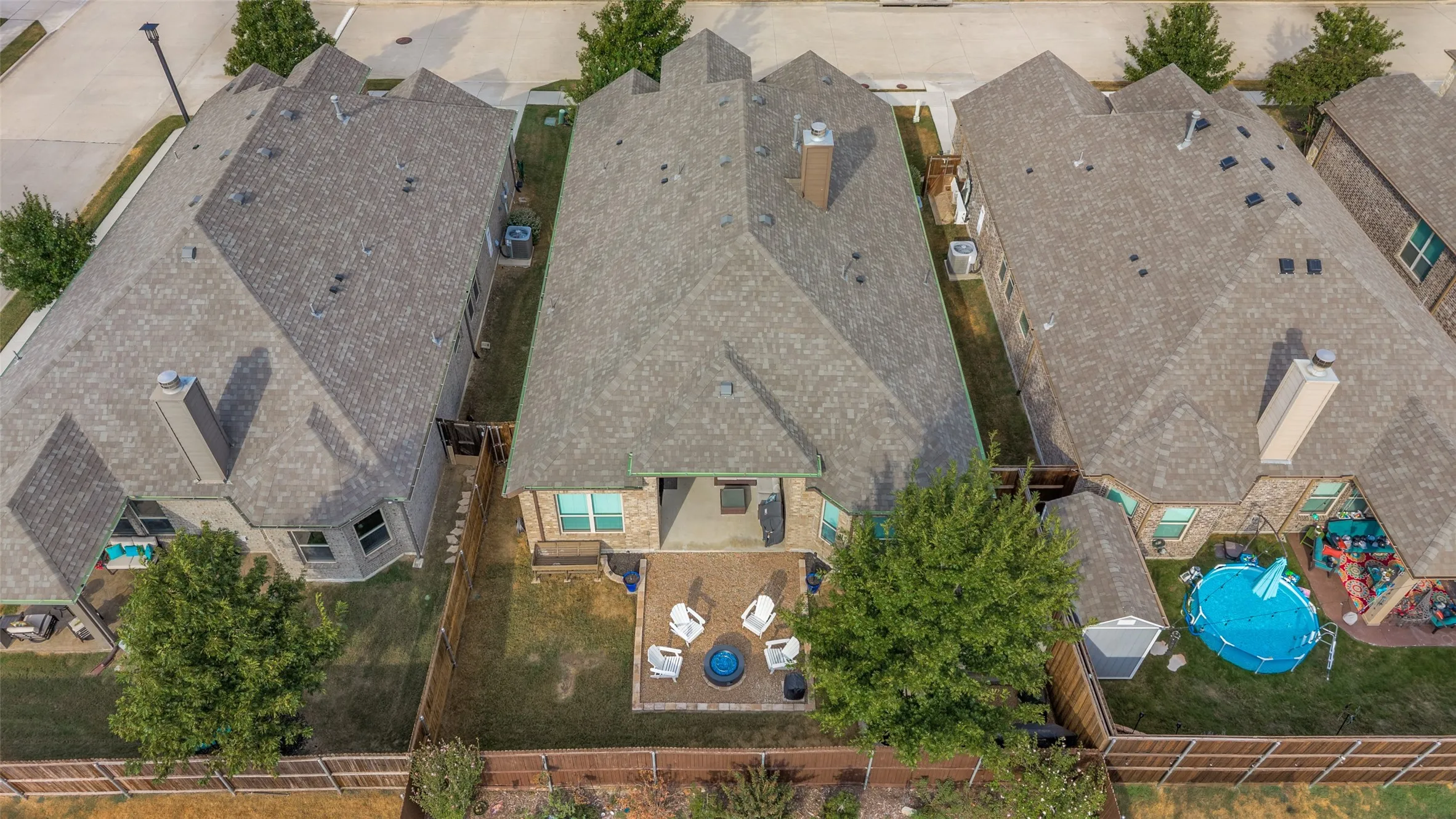 Expansive backyard with a covered patio, paved seating area, and established tree