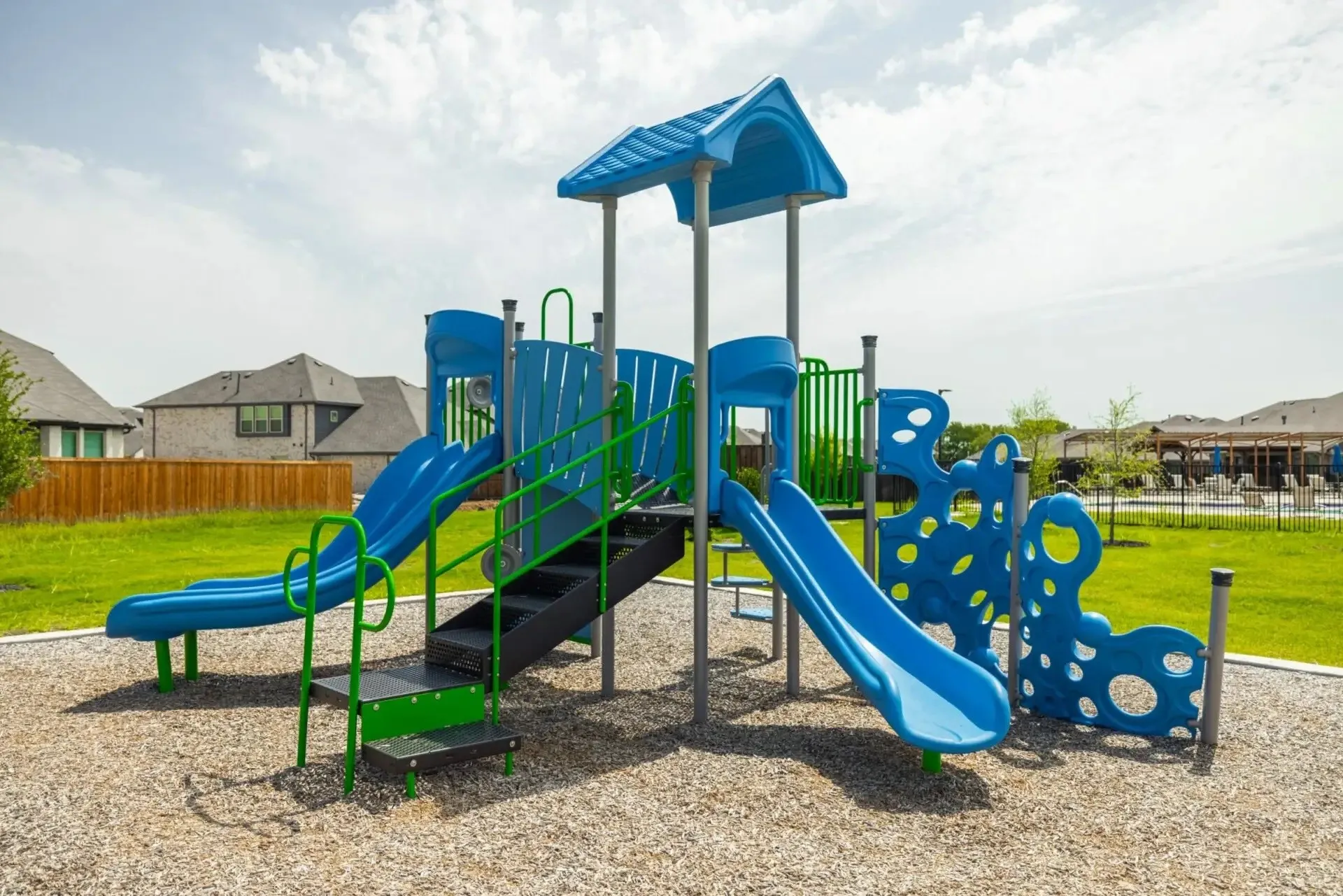 Recreational playground featuring two slides, stairs, a climbing element, and a protective ground surface