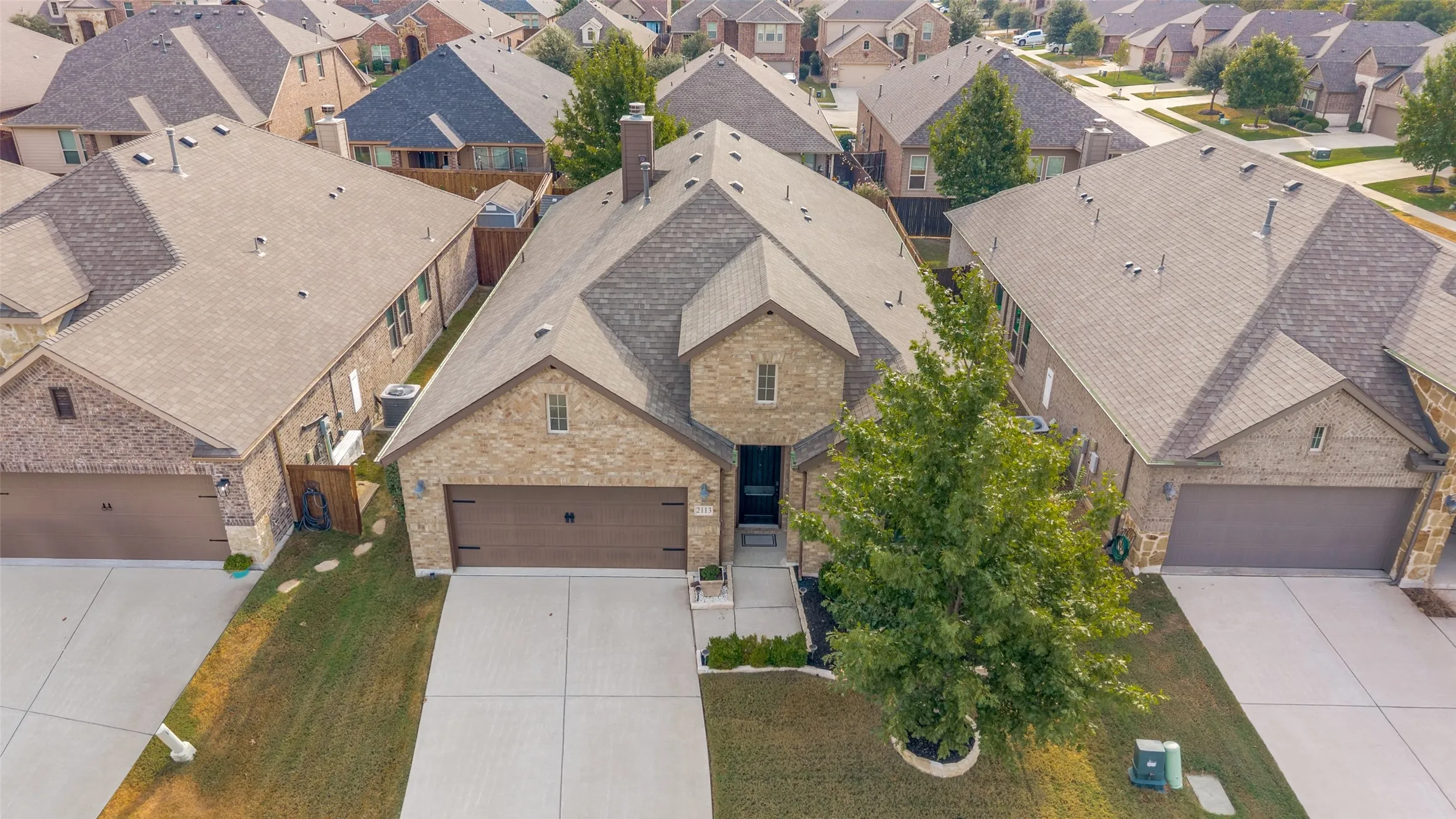 Brick exterior, two-car garage, concrete driveway, front yard landscaping, mature tree