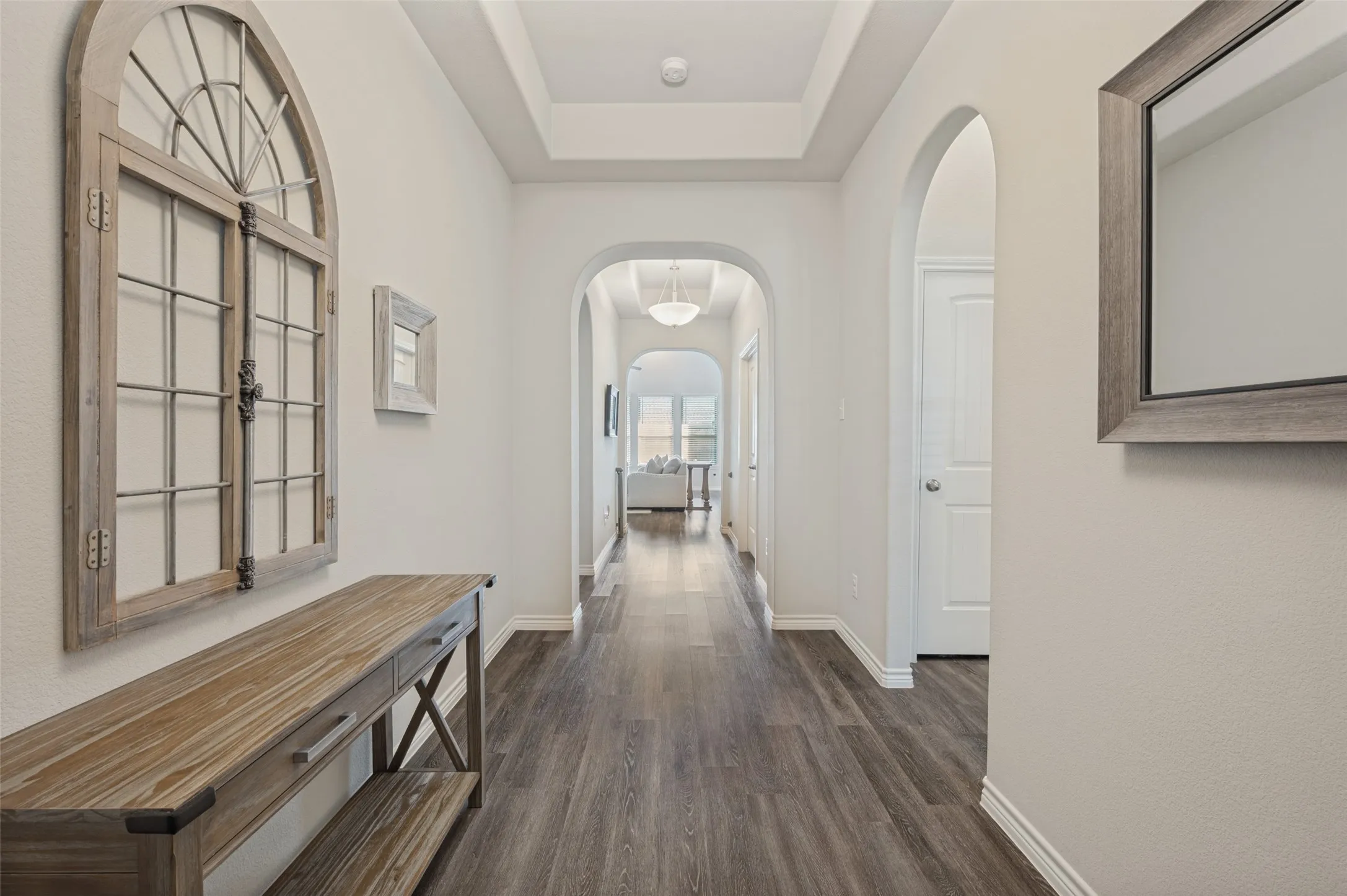 Wood-finish flooring, recessed lighting, arched doorways, and tray ceiling