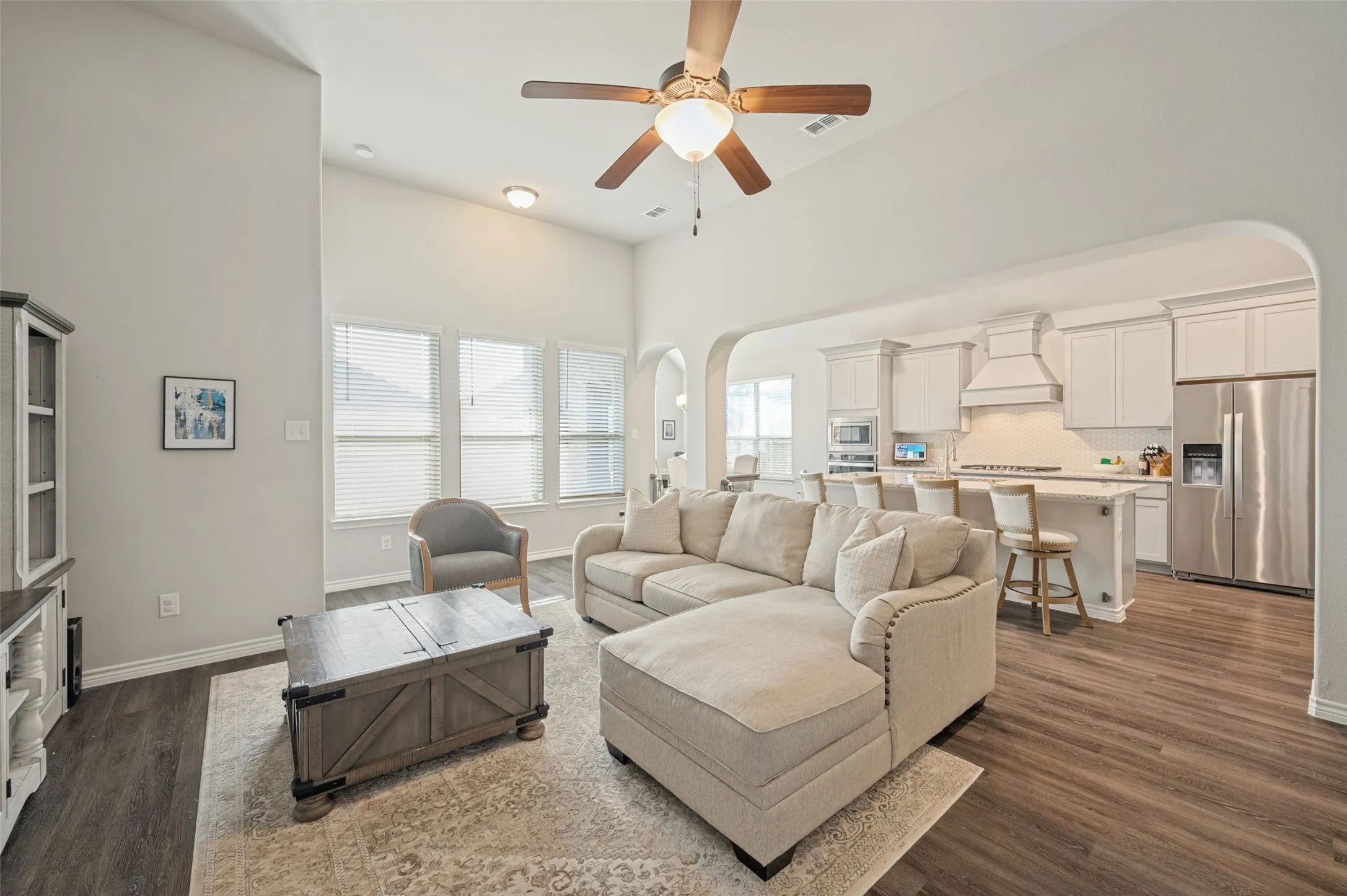 High vaulted ceiling, wood-finish flooring, ample natural light from multiple windows, recessed lighting, and a ceiling fan
