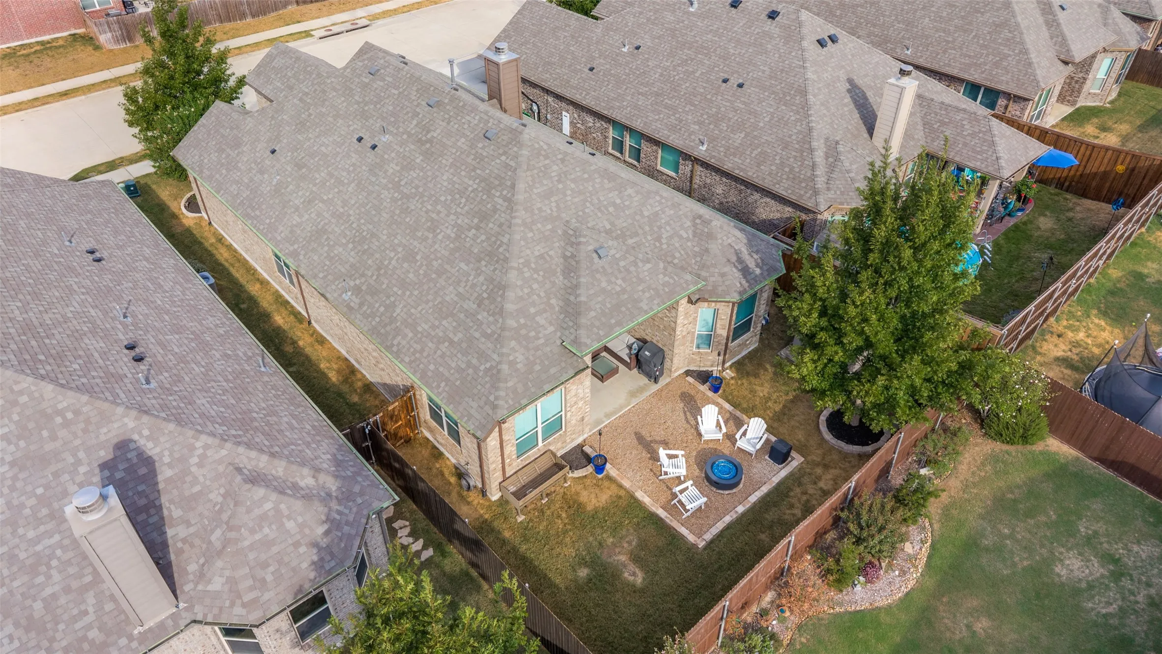 Brick exterior with a gabled roof, featuring a paver patio, stone fire pit, and mature landscaping