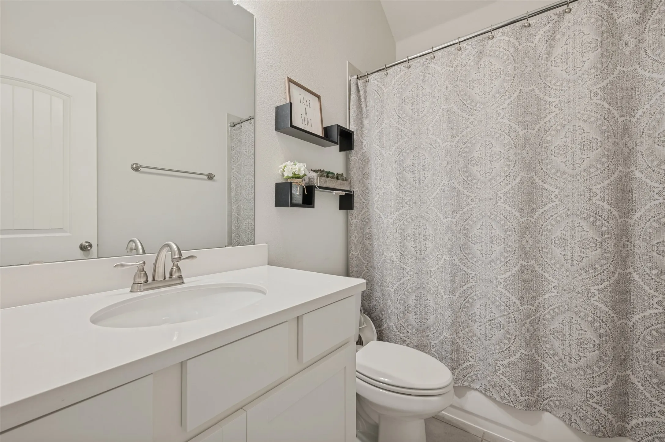 Vanity with integrated sink, brushed nickel faucet, large mirror, and tiled shower/tub combination