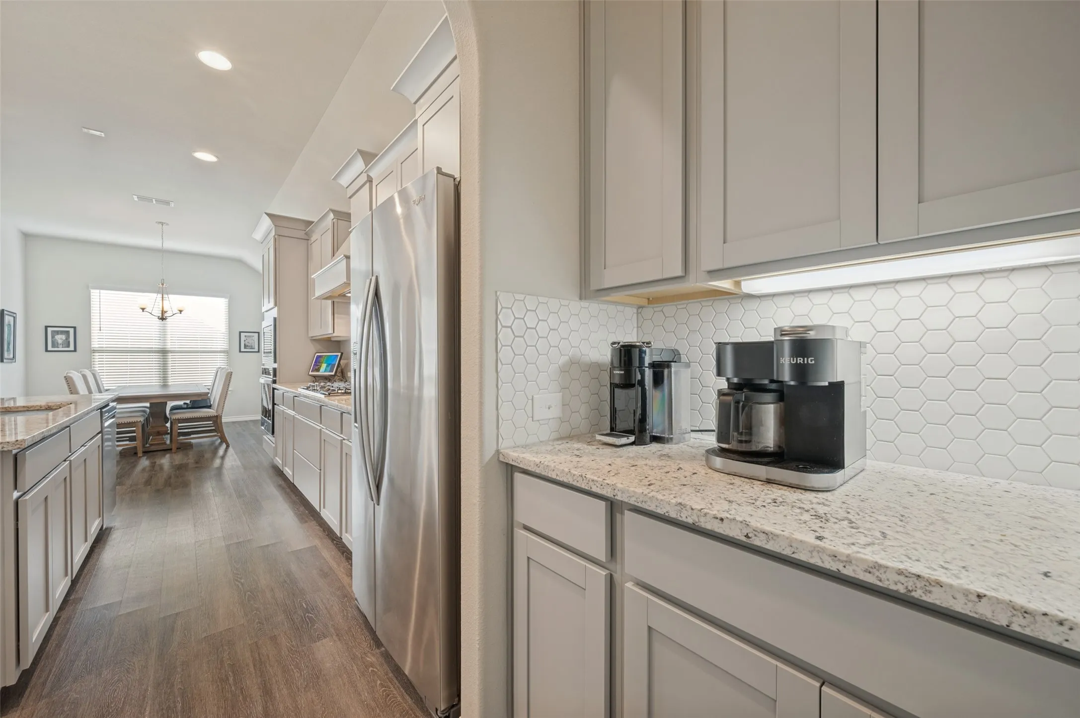 Coffee Bar off the kitchen, light gray shaker cabinetry, wood-finish flooring, recessed lighting, and a white hexagonal tile backsplash