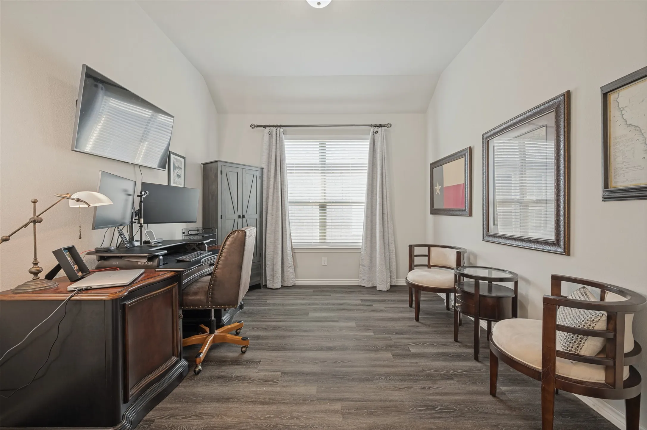 Vaulted ceiling with a central light fixture, wood-finish flooring, and a window with blinds and drapes