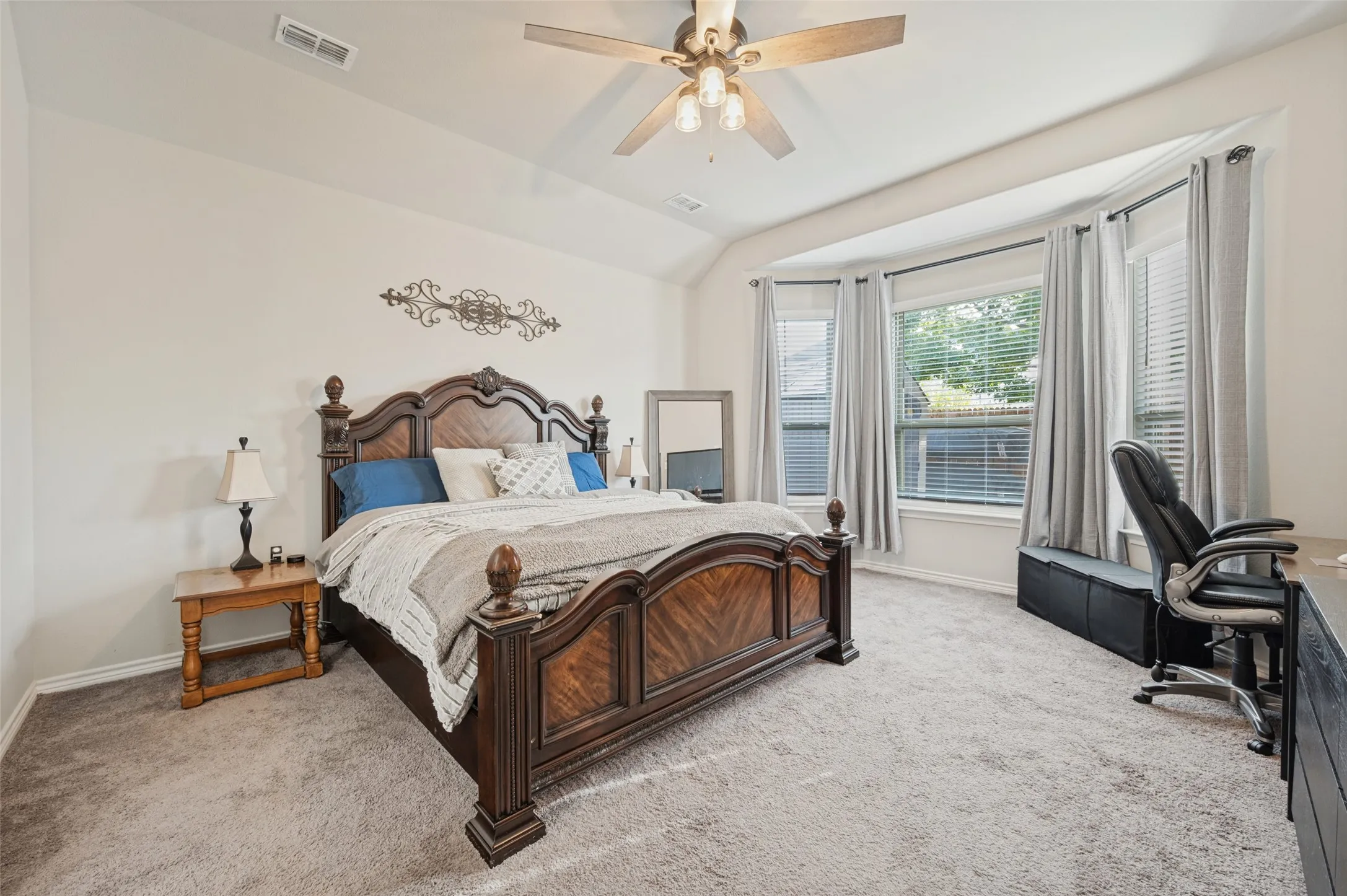 Carpeted bedroom with a vaulted ceiling, a bay window, and a ceiling fan with integrated lighting