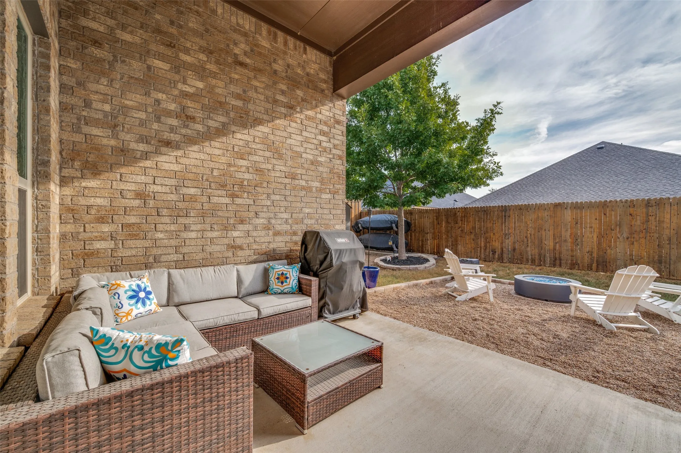 Covered patio with brick exterior, concrete flooring, and a fenced backyard