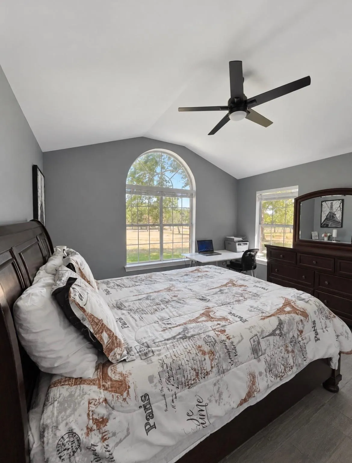 Vaulted ceiling with an integrated ceiling fan, arched window, additional windows, and wood-finish flooring