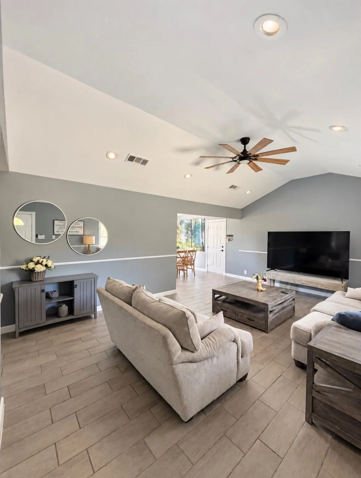 Vaulted ceiling, recessed lighting, ceiling fan, wood-look tile flooring, and a two-tone wall finish