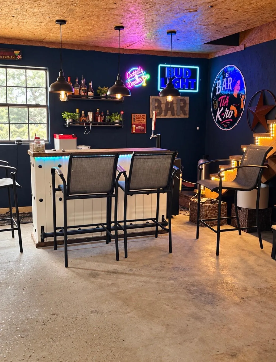 Finished concrete flooring with a built-in bar featuring a light wood countertop and integrated lighting