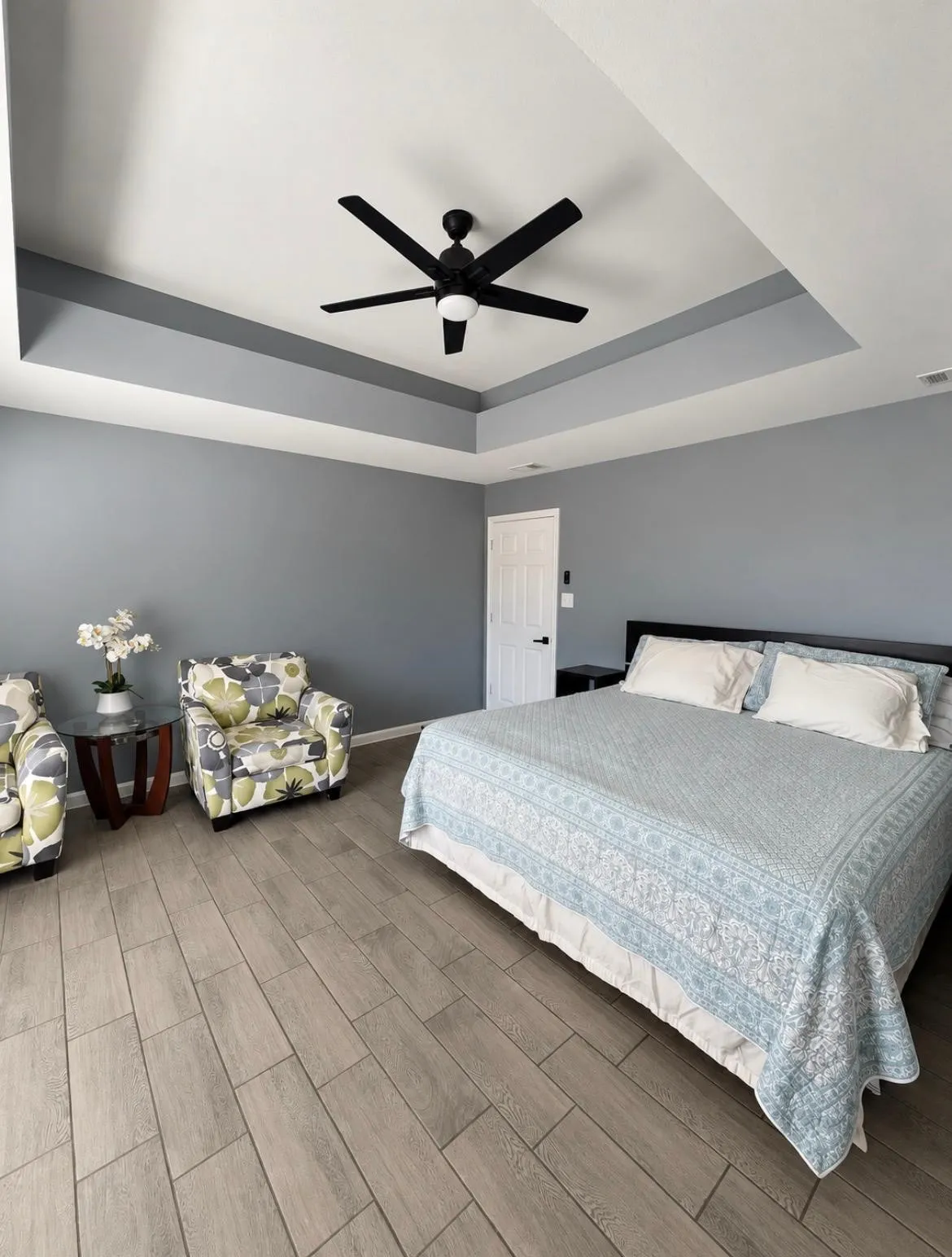 Tray ceiling with a ceiling fan, wood-finish flooring, and white interior door