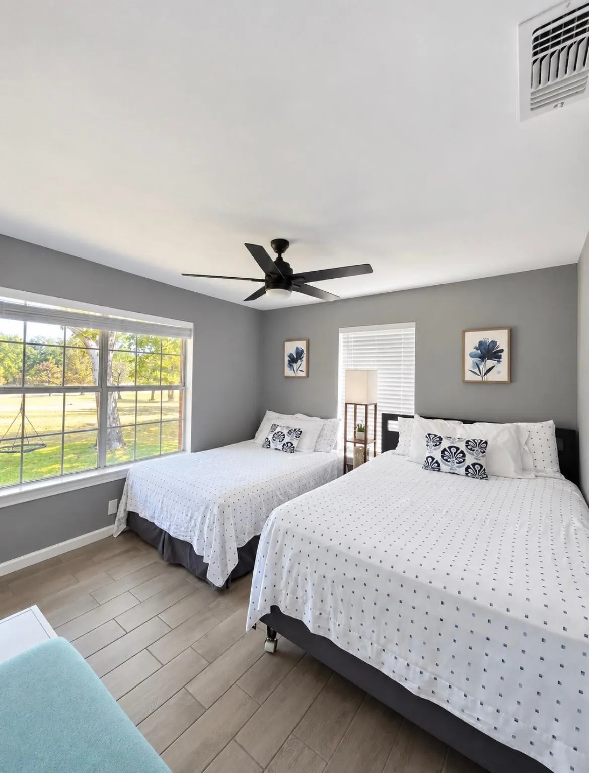 Spacious room featuring wood-finish flooring, multiple windows, a ceiling fan, and wall-mounted air conditioning