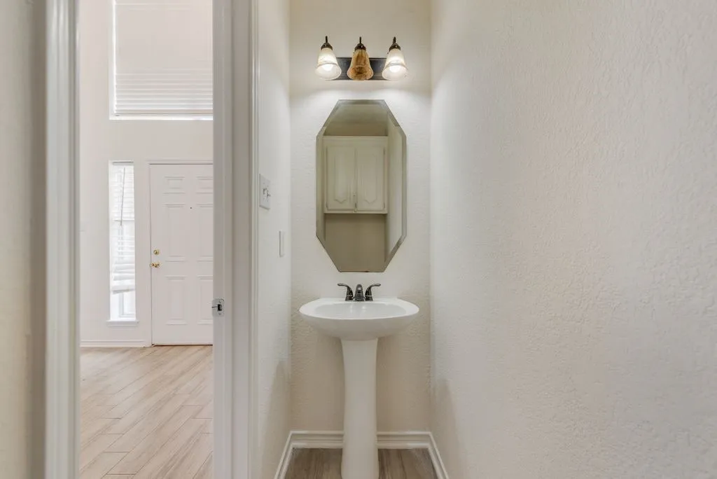 Pedestal sink with an octagonal mirror and a three-light vanity fixture