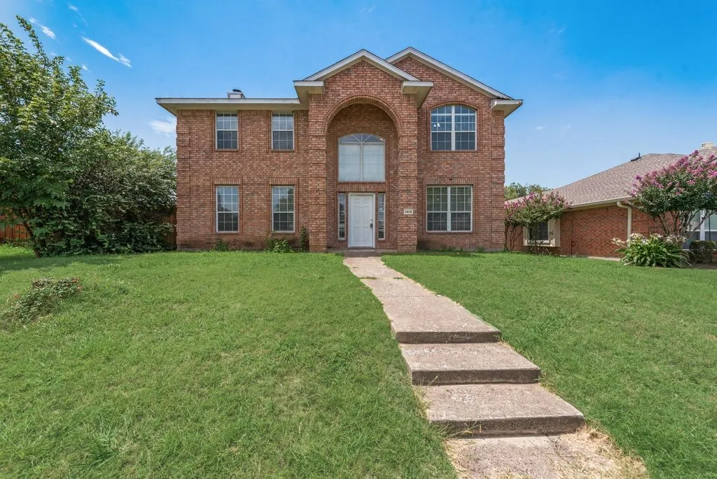 Two-story brick facade residence with a prominent arched entry and a multi-level concrete walkway