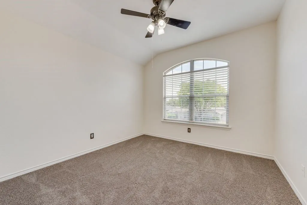 Carpeted room with an arched window featuring horizontal blinds